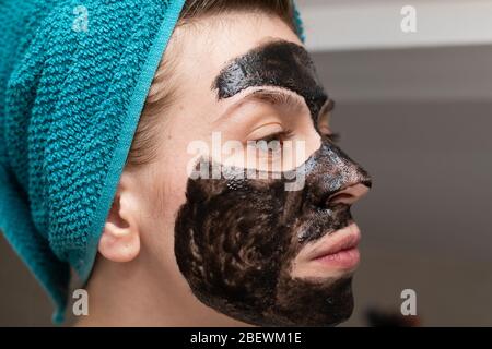 Nahaufnahme Porträt der Frau Anwendung schwarze Holzkohle Gesichtsmaske im Badezimmer - tägliche Hautpflege Routine Stockfoto