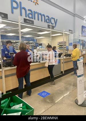 SPRINGFIELD, MO, USA-15. April 2020 Käufer in einer Walmart Apotheke während der COVID-19-Pandemie. Schilde vor Mitarbeitern und soziale Distanzmarkierungen auf dem Boden. Stockfoto