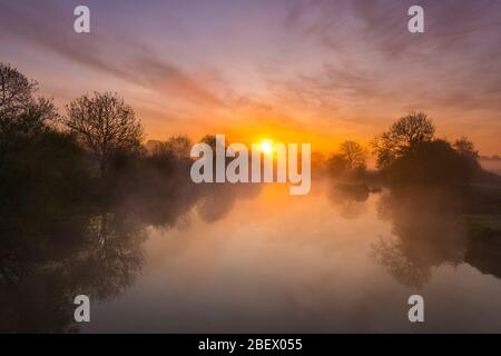 Wimborne, Dorset, Großbritannien. April 2020. Wetter in Großbritannien. Ein spektakulärer Sonnenaufgang spiegelt sich im River Stour an der Eye Bridge in Wimborne in Dorset wider, während der Nebel aus dem Wasser steigt. Bild: Graham Hunt/Alamy Live News Stockfoto