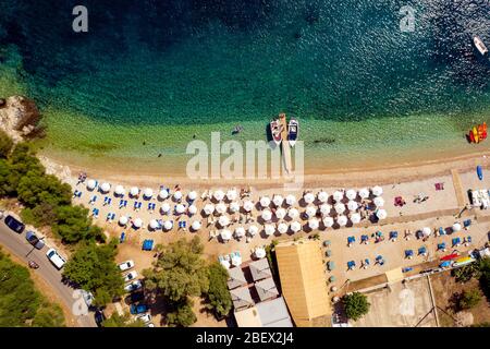 Antenne eines Strandes mit Sonnenschirmen und Booten in Griechenland. Mediterranes Seebad. Paradies Lagune mit türkisfarbenem Wasser Stockfoto