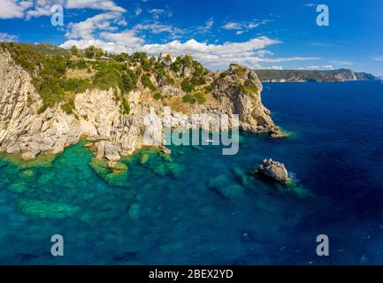 Luft mediterrane Landschaft mit türkisfarbenem Meer. Blick auf eine Insel Korfu in Griechenland. Paleokastritsa Kloster von einer Drohne. Boot mit Touristen auf einem Be Stockfoto