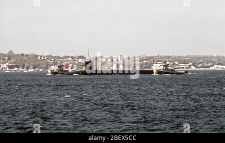 1981 - ein Hafen Blick auf die nuklearen ballistischen Raketen-U-Boots OHIO (SSBN-726) durch zwei große Schlepperflotte nach ihrer endgültigen Meer Prüfungen vor Inbetriebnahme begleitet werden. Die Schlepper sind die METACOM (YTB-4626) und der NEGWAGON (YTB-529). Das U-Boot wurde von General Dynamics Corp. gebaut Stockfoto