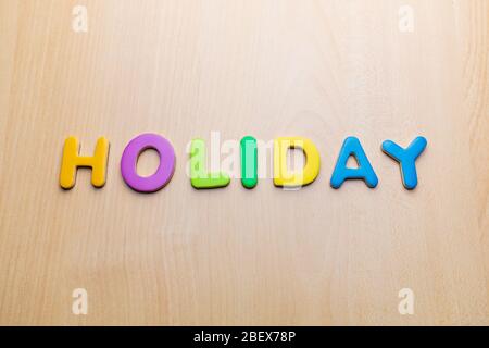 Urlaubswort mit bunten Buchstaben auf Holztisch Hintergrund geschrieben, Text Stockfoto