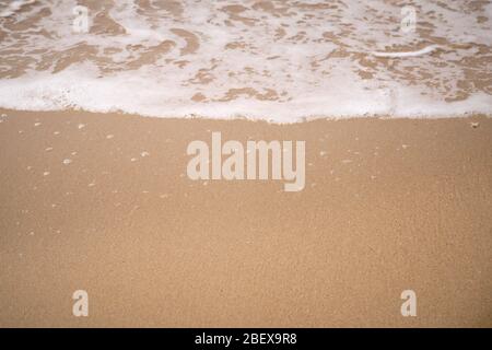 Ruhige Wellen, die an einem sonnigen Tag über einem Strand liegen Stockfoto