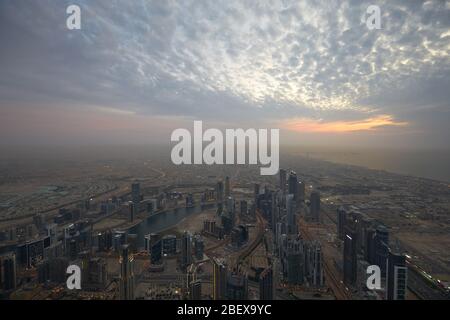 DUBAI, VEREINIGTE ARABISCHE EMIRATE - 19. NOVEMBER 2019: Dubai Stadt Hochwinkel Blick mit Wolkenkratzern bei Sonnenuntergang, wolkiger Abend vom Burj Khalifa Stockfoto