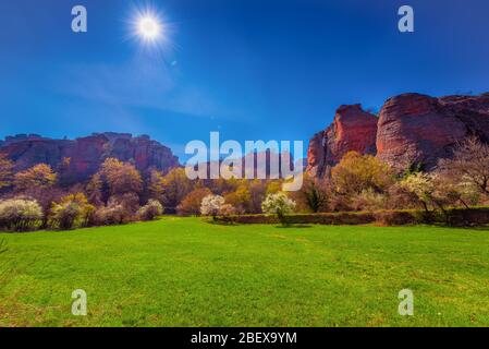 Sonniger Tag in der schönen Schlucht-wie Belogradchik (Westbulgarien) mit seinen grünen Feldern voller Bäume und phänomenale Sandsteinfelsen Stockfoto