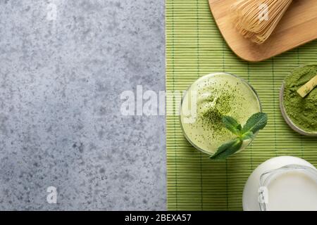 Dalgona Iced Matcha Tee. Geschlagenes weißes Ei mit Matcha-Tee wird der Milch mit Eis hinzugefügt. Schmackhaftes virales Getränk in der Zeit Selbstisolierung. Blick von oben. Stockfoto