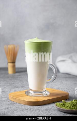 Dalgona Iced Matcha Tee. Geschlagenes weißes Ei mit Matcha-Tee wird der Milch mit Eis hinzugefügt. Schmackhaftes virales Getränk in der Zeit Selbstisolierung. Vertikales Format. Stockfoto