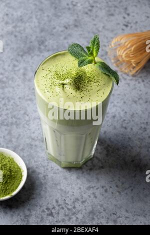Dalgona Iced Matcha Tee. Geschlagenes weißes Ei mit Matcha-Tee wird der Milch mit Eis hinzugefügt. Schmackhaftes virales Getränk in der Zeit Selbstisolierung. Vertikales Format. Stockfoto