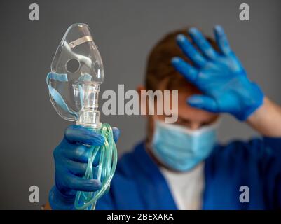 COVID-19 Ausbruch. Erschöpfter Arzt mit nichtinvasivem Beatmungsgerät. Medizinische Behandlung und Mangel an Ausrüstung für Coronavirus-infizierte Patienten mit S Stockfoto