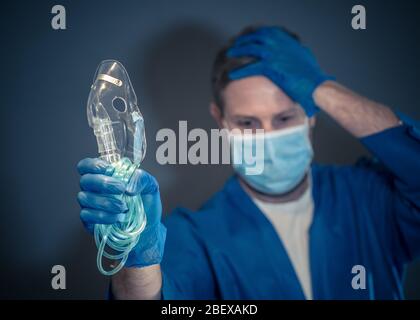 COVID-19 Ausbruch. Erschöpfter Arzt mit nichtinvasivem Beatmungsgerät. Medizinische Behandlung und Mangel an Ausrüstung für Coronavirus-infizierte Patienten mit S Stockfoto