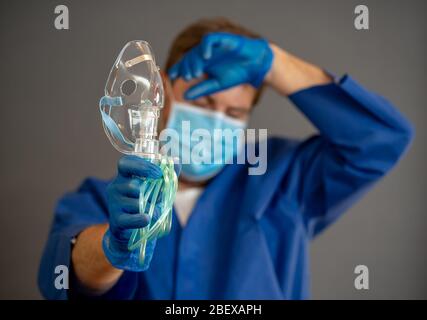 COVID-19 Ausbruch. Erschöpfter Arzt mit nichtinvasivem Beatmungsgerät. Medizinische Behandlung und Mangel an Ausrüstung für Coronavirus-infizierte Patienten mit S Stockfoto