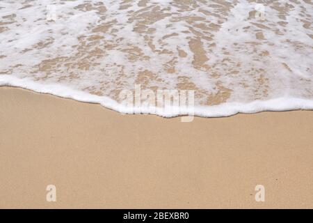 Ruhige Wellen, die an einem sonnigen Tag über einem Strand liegen Stockfoto