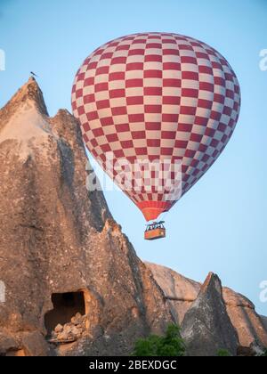 Rot-weißer Heißluftballon über Höhlenhaus in kappadokien Stockfoto