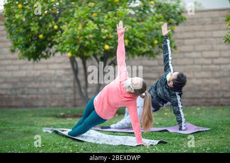 Junges Paar Yoga praktizieren Kleidung Gesichtsmasken tragen. Viele Länder empfehlen Bürgern, während des Weltkronavirus Covid-19 ihre Gesichter zu bedecken Stockfoto