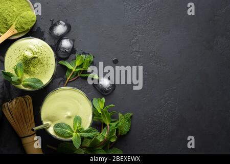 Zwei Gläser Dalgona Iced Matcha Tee und Zutaten auf schwarzem Hintergrund. Kopierbereich. Blick von oben. Stockfoto