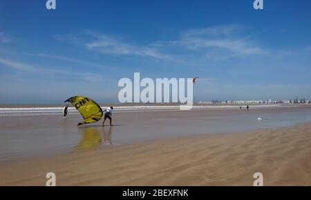 Essaouira//Marokko - 10.01.2019: Mann, der seine Kitesurfausrüstung auf dem Plage Tagharte in Essaouira trägt. Stockfoto