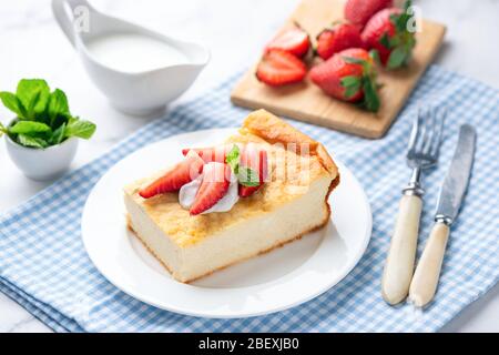 Quark Kasserolle, Zapekanka mit Sahne und Erdbeeren serviert. Gesundes Frühstück oder Snack Kuchen reich an Protein und Kalzium aus Cottage ch gemacht Stockfoto