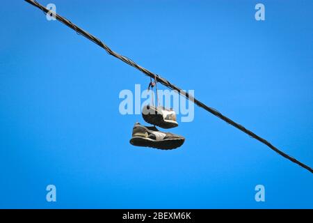 Ein Paar alte Turnschuhe auf Telefonleitungen in der Stadt. Stockfoto
