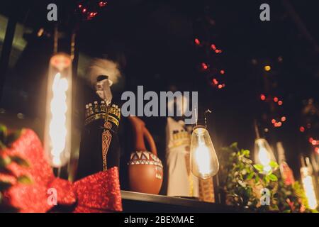 Tisch mit dekorativen Objekten und Hörner-Gefäße für Wein trinken auf dem Hintergrund eines Fasses Wein in einem thematischen Innenraum Stockfoto