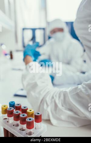 Selektiver Fokus von Reagenzgläsern mit Blutproben in der Nähe von Biochemikern im Labor Stockfoto