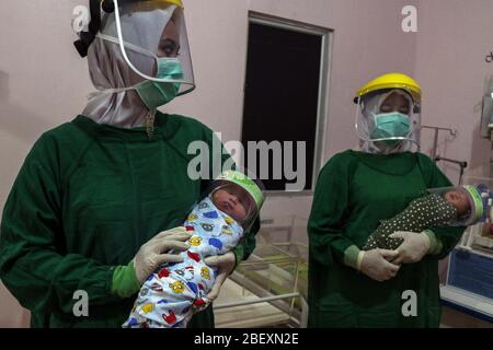 Aceh, Indonesien. April 2020. Zwei indonesische Krankenschwestern halten ein neugeborenes Baby mit Gesichtsschutz in einem Krankenhaus im Bezirk Bireuen, Provinz Aceh, Indonesien, Donnerstag, 16. April 2020. Tragen von Schutzschilden war Anstrengung zu verhindern, dass die Ausbreitung von Coronavirus Covid-19 . (Foto: Aziz Abdi/INA Photo Agency/Sipa USA) Quelle: SIPA USA/Alamy Live News Stockfoto