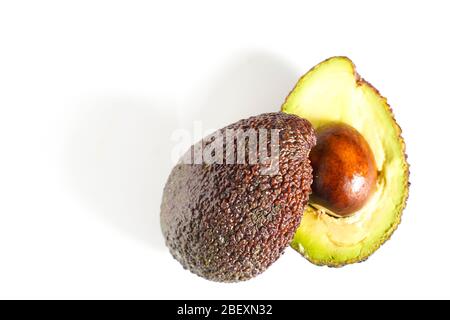 Ein Avocado, das in zwei Hälften geschnitten wurde, um den Kern vor einem weißen Hintergrund zu enthüllen Stockfoto