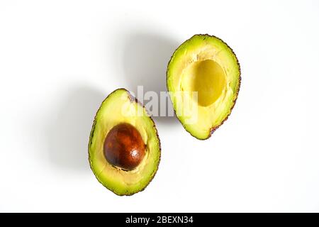 Ein Avocado, das in zwei Hälften geschnitten wurde, um den Kern vor einem weißen Hintergrund zu enthüllen Stockfoto