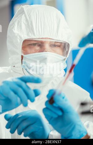 Teilansicht des Biochemikers, der Pipette und Reagenzglas mit Blutprobe in der Nähe eines Kollegen hält Stockfoto