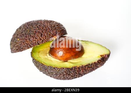 Ein Avocado, das in zwei Hälften geschnitten wurde, um den Kern vor einem weißen Hintergrund zu enthüllen Stockfoto