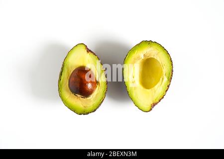 Ein Avocado, das in zwei Hälften geschnitten wurde, um den Kern vor einem weißen Hintergrund zu enthüllen Stockfoto