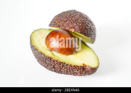 Ein Avocado, das in zwei Hälften geschnitten wurde, um den Kern vor einem weißen Hintergrund zu enthüllen Stockfoto