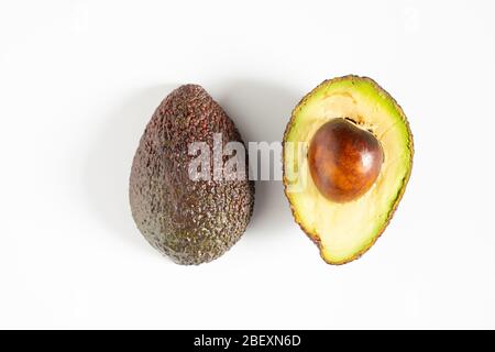 Ein Avocado, das in zwei Hälften geschnitten wurde, um den Kern vor einem weißen Hintergrund zu enthüllen Stockfoto