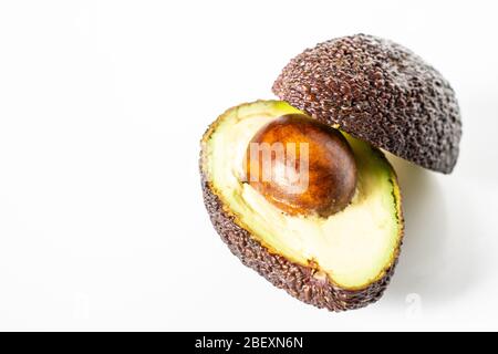 Ein Avocado, das in zwei Hälften geschnitten wurde, um den Kern vor einem weißen Hintergrund zu enthüllen Stockfoto