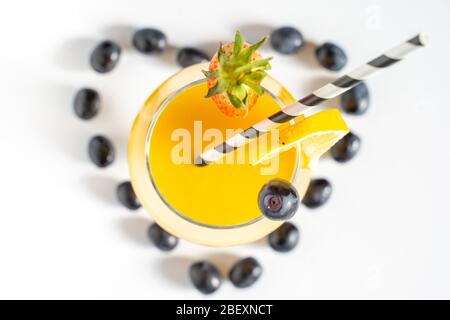 Schwarze Trauben in Form eines Liebesherzens mit einem orangefarbenen Cocktail in der Mitte vor einem schlichten weißen Hintergrund Stockfoto
