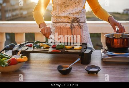 Junge Frau Grill Gemüse während der Vorbereitung Abendessen auf der Terrasse im Freien während der Isolation Quarantäne - Essen, gesunder Lebensstil und vegetarische Konz Stockfoto