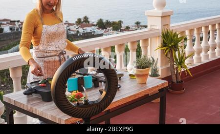 Junge Frau Koch Kochen im Freien während Streaming online für Webinar Masterclass Lektion zu Hause - Weibliche Herstellung Videos Vorbereitung vegetarische Mahlzeit während Stockfoto