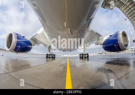 Das Passagierflugzeug wird auf dem Vorfeld des Flughafens geparkt. Flugzeugrumpf, Motor und Hauptfahrwerk Stockfoto