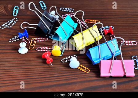 Knöpfe, farbige Büroklammern, Büroklammern auf einem natürlichen braunen Hintergrund Stockfoto