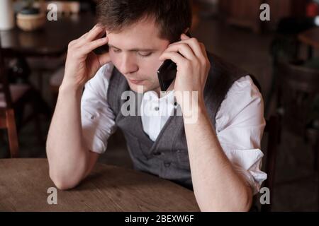 Schöner Mann mit einem harten Gespräch am Telefon versucht, ruhig zu bleiben Stockfoto
