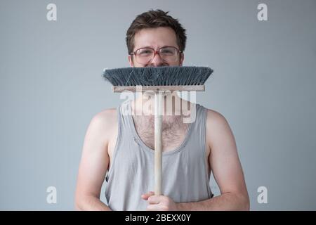 Junger Mann steht bereit für die Reinigung Boden mit Mopp. Studioaufnahme Stockfoto