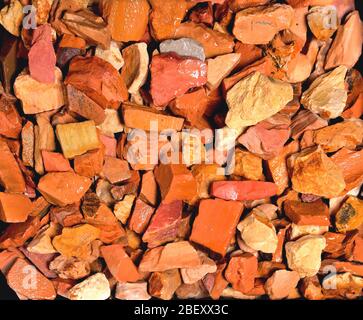 Nasse kleine uneinheitliche Steine von rot-rosa Farbe mit rechteckigen Flächen, Hintergrund, Textur Stockfoto