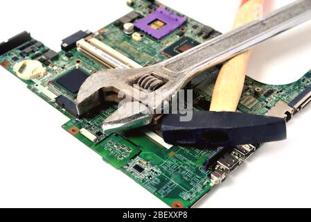 Hammer und Schraubenschlüssel auf einem alten Mikrokreis für einen Computer auf weißem Hintergrund, Nahaufnahme Stockfoto