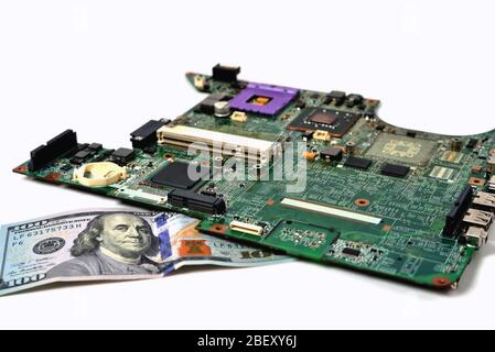 Ein alter Chip aus einem Laptop liegt auf einer Rechnung von hundert Dollar, einem weißen Hintergrund, einer Nahaufnahme Stockfoto