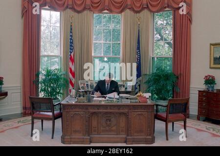 7/15/1988 Präsident Reagan an seinem Schreibtisch im Oval Office arbeiten Stockfoto