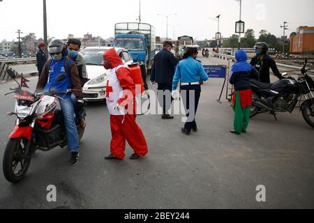 Kathmandu, Nepal. April 2020. Eine Frau vom Roten Kreuz desinfiziert Fahrzeuge an einem Polizeikontrollpunkt entlang der Grenze von Kathmandu und Bhaktapur am 24. Tag einer Regierung, die am Donnerstag, dem 16. April 2020, wegen der Ausbreitung der Coronavirus-Ansteckung in Nepal eine Sperre verhängt hat. Kredit: Skanda Gautam/ZUMA Wire/Alamy Live News Stockfoto