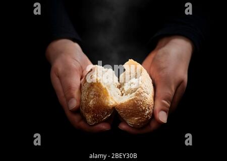 Hände brechen ein frisches, noch dampfendes Brötchen... Stockfoto