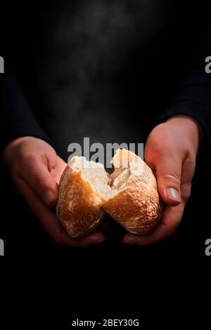 Hände brechen ein frisches, noch dampfendes Brötchen... Stockfoto