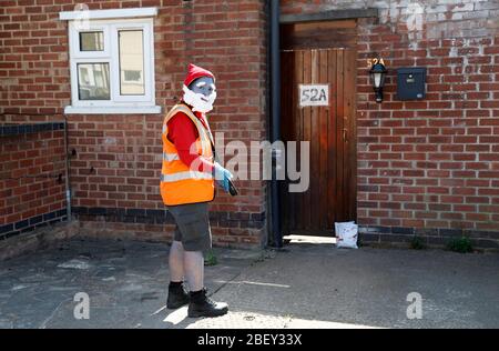 Loughborough, Leicestershire, Großbritannien. April 2020. Eine Postfrau aus Royal Mail trägt ein Smurf-Kleid zur Unterstützung des NHS, während sie während der Sperrung der Coronavirus-Pandemie Post abliefert. Credit Darren Staples/Alamy Live News. Stockfoto