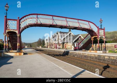 Die traditionell gestaltete Fußgängerbrücke und Bahnhof an der Settle auf der berühmten Settle Carlisle Bahnlinie Stockfoto